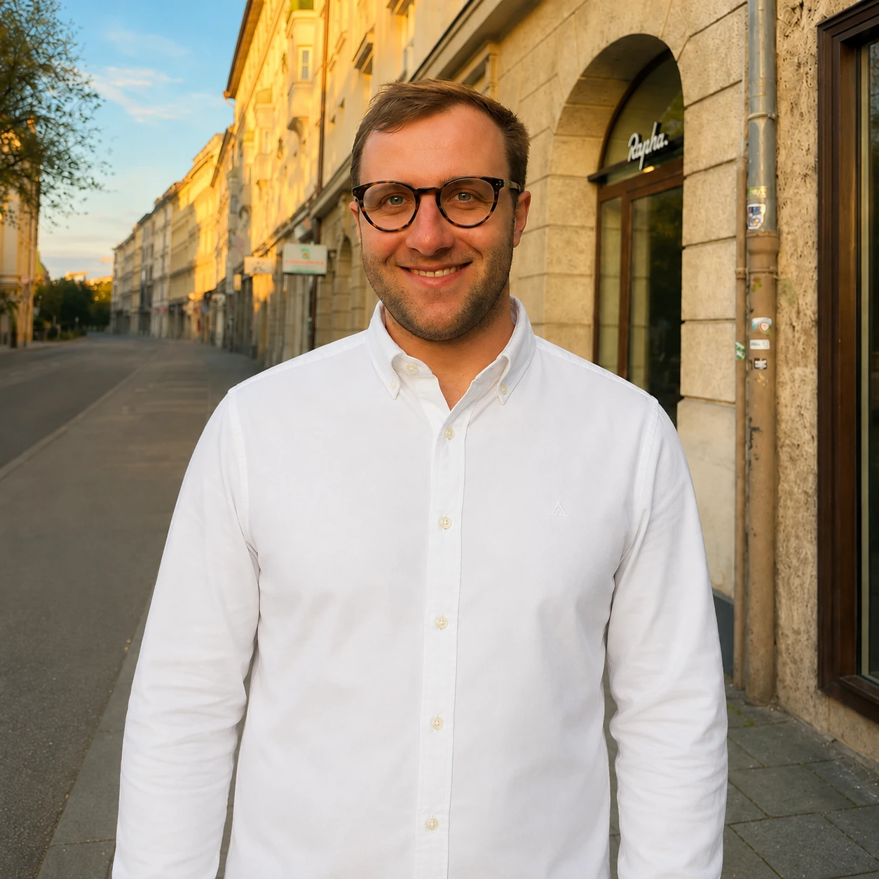 Geschäftsführer von MINT Makler: Michael Bruckschlegel steht in der Golden Hour auf einer Straße und lächelt in die Kamera